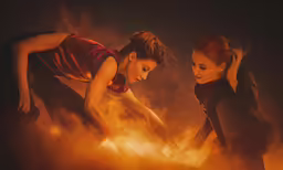 two women in black clothes working on a large object