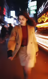 a young woman in an ivory coat is going down a city street at night