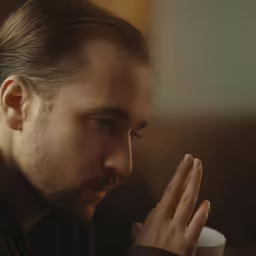 a man holding a cup of coffee and looking at it