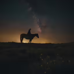 the night sky with stars and a silhouette of a cowboy riding a horse