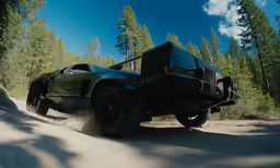 a green and black car is making a turn on a hill