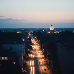 a street with traffic at night time and buildings in background