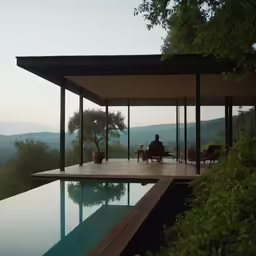 a view from a pool of people sitting on a bench looking out over the mountains