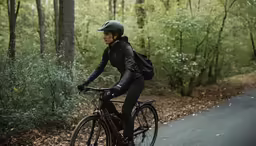a woman in black riding on top of her bike