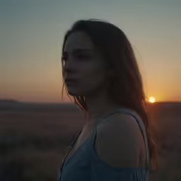 a young girl standing in a field looking to the sky
