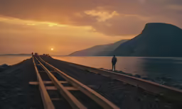 a person standing on train tracks at sunset