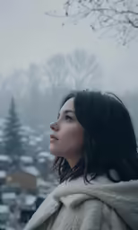a woman in winter clothes looks over a city