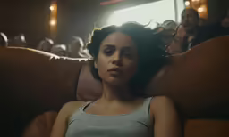 a woman laying down on the couch with people watching