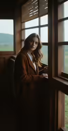 a woman leaning against a window in a barn