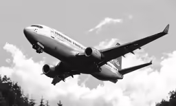 an air plane flying in the sky with trees below