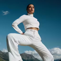 the beautiful woman is wearing white outfit and poses with her hands on her hips