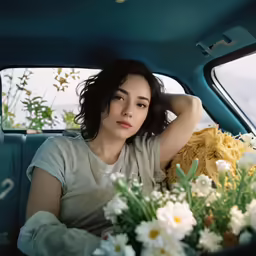 a woman sitting in the passenger seat of a car next to flowers