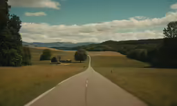 an empty country road and barn in the distance