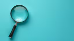 a magnifying glass sitting on top of a turquoise background,a magnifying glass is laying on the surface