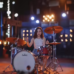 a person playing the drums in front of some lights