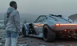 a person standing near an unfinished sports car