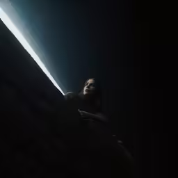 a person sits on the edge of a cliff under the moonlight