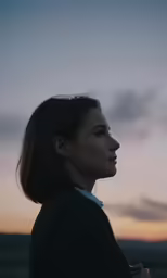 a woman looking off into the distance with a sky behind her