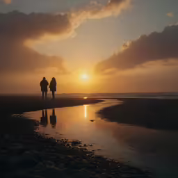 the sun is setting over the water as two people walk on a beach