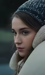 a young woman with blue eyes wearing a large winter hat