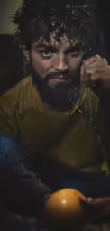a man holding an orange next to his face