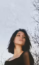 a young woman is in front of a barren tree