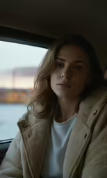 a woman sitting in the backseat of a vehicle while she stares into the distance