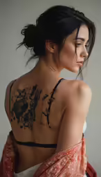 a woman with tattoos standing by a wall