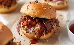 an open - faced hamburger topped with meat, barbecue sauce and sesame seeds