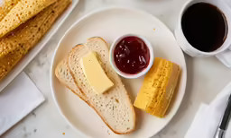 a plate with bread, jam and a cheese wedge