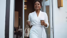 an african american woman in white and holding a cup of coffee