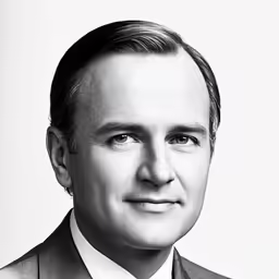 a man in a suit and tie smiling at the camera