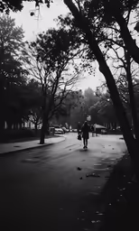 a man is walking down a street past trees