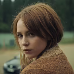 a girl in brown sweater looking at the camera