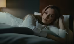 a woman laying in bed with her head on her arm