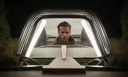 a man sitting in the back seat of a car looking into a truck