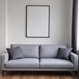 a modern grey couch with blank paper hanging on the wall