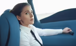 a woman wearing a neck tie is sitting in the backseat