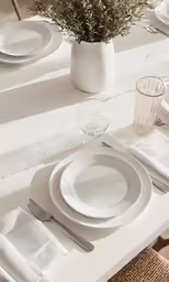 a white table with two napkins and glasses with flowers on the plate