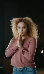 a girl with blonde hair is praying in the dark