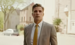 a young man in a tan suit and tie