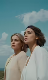 two beautiful women standing next to each other on the beach