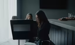 two women sitting down at a table in front of a computer
