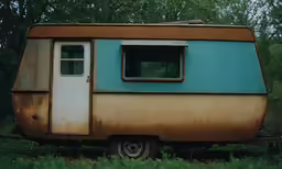a trailer with a small window and small door in a grassy area