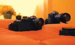 an orange bed with two different cameras on top