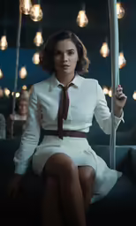a young woman in white dress posing on a couch with lights