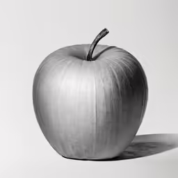 the gray apple is laying flat on the white surface