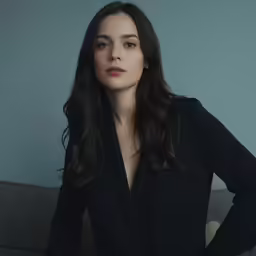 an attractive woman with dark hair posing on a couch