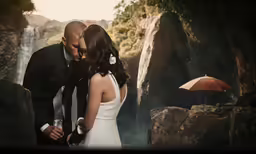 a man and woman standing by the water in formal wear