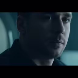 man looks into the camera while staring intently at something